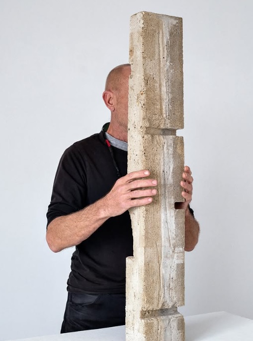 Franck Roux tenant une sculpture verticale en béton